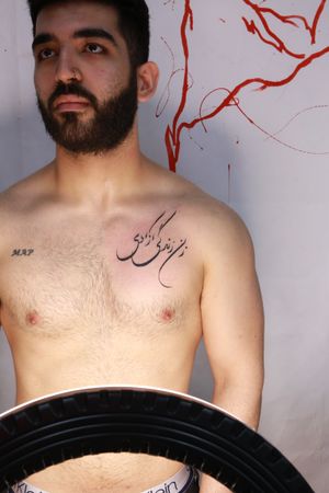 Jamie B's blackwork chest tattoo features a powerful Arabic quote beautifully crafted in intricate lettering.