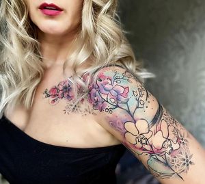 Elegant upper arm tattoo blending intricate dotwork mandala with vibrant watercolor flower by VV Swain Tattoo.