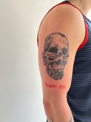 This small lettering blackwork tattoo featuring a skull and quote is the perfect addition to your upper arm. Created by talented artist Jamie B.