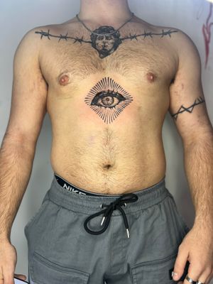 Exquisite blackwork tattoo by Jamie B, featuring intricate eye motif in a bold chest placement.
