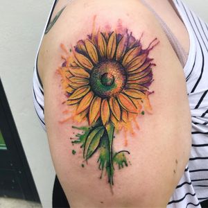 Get a stunning and colorful sunflower tattoo on your upper arm by the talented VV Swain Tattoo.