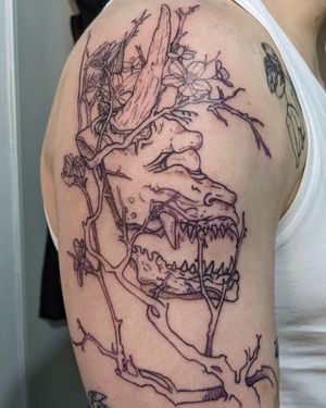 Beautifully detailed upper arm tattoo featuring a fine line design of a dragon intertwined with a delicate flower, created by artist Frankie Brown.