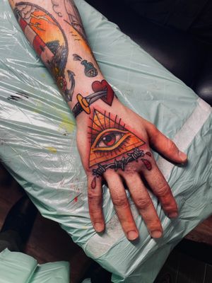 Vibrant neo traditional hand tattoo featuring a captivating triangle and eye design by Frankie Brown.