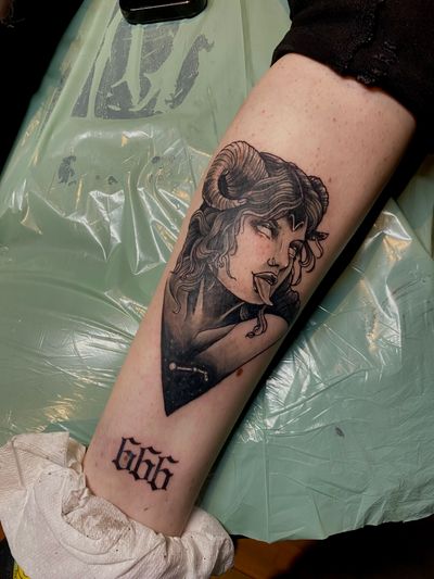 A striking blackwork tattoo on the forearm featuring a devil and woman, masterfully executed by artist Frankie Brown.