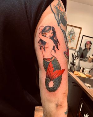 Get a stunning traditional mermaid tattoo on your upper arm by the talented artist Frankie Brown. Embrace the mythical beauty and grace of the sea with this timeless design.