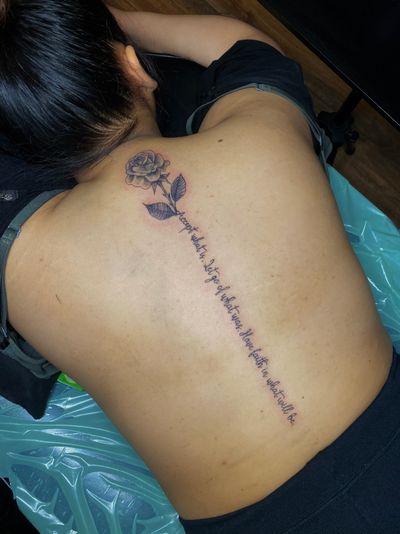 Small lettering and intricate black & gray rose design, perfect for the back, symbolizing beauty and inspiration.