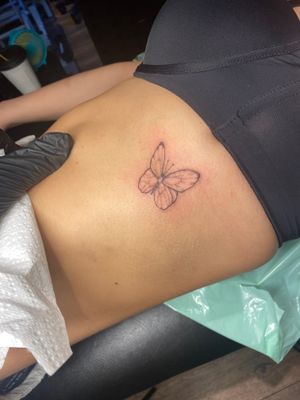 Beautiful fine line butterfly tattoo on ribs by artist Frankie Brown, showcasing elegance and grace.