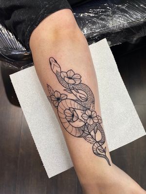 Exquisite dotwork design featuring a snake, flowers and plants by Joanna Webb. Perfect for a unique and elegant forearm piece.