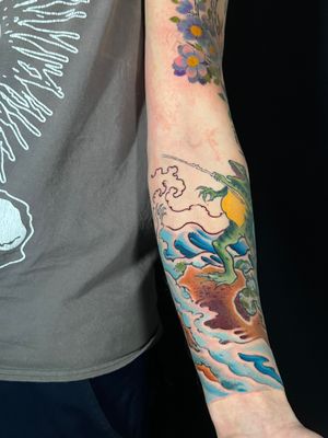 Get a vibrant new school tattoo of a frog riding waves by Kiko Lopes on your forearm.