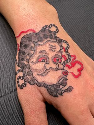 Elevate your style with a stunning Japanese charm head tattoo on your hand. Designed by the talented artist Kiko Lopes.