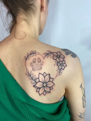 Unique upper back tattoo by Joanna Webb featuring a beautiful combination of floral, heart, and paw motifs in a dotwork and geometric style.