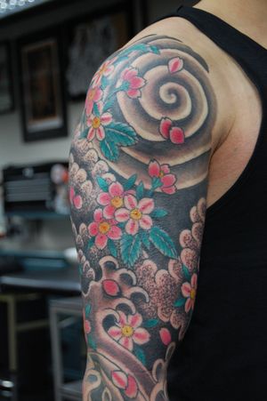 Experience the beauty of Japanese art with this stunning upper arm tattoo by Bananajims. Featuring intricate flowers and flowing waves, this design is sure to make a statement.