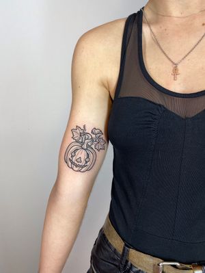 Get into the spooky spirit with this fine line pumpkin and leaf upper arm tattoo by Joanna Webb. Perfect for Halloween!