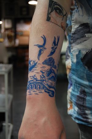 Beautiful forearm tattoo featuring a Japanese-style bridge with birds, done by the talented artist Bananajims.