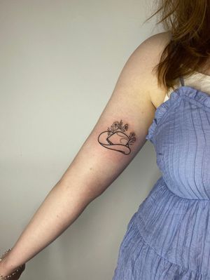 Beautiful fine line floral tattoo featuring a flower, hat, and plants by Joanna Webb. Perfect for those seeking a sophisticated and botanical-inspired design.