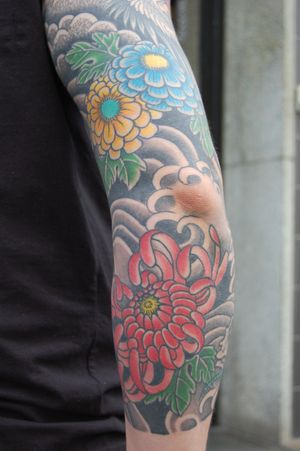 Beautiful sleeve tattoo featuring intricate Japanese peony flowers by Bananajims. Adorn your arm with vibrant colors and timeless art.