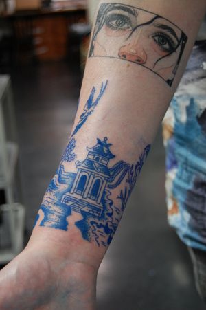 Impressive forearm tattoo featuring a beautiful bird and intricate architectural design, by renowned artist Bananajims.