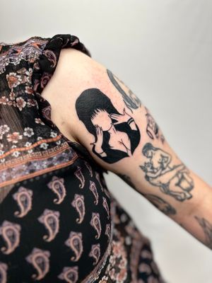 Get a stunning blackwork tattoo of Elvira on your upper arm by the talented artist, Miss Vampira.