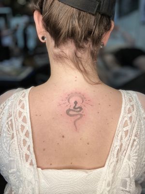 Elegant dotwork tattoo on upper back featuring a mystical moon and slithering snake by Viví Bogdanov.