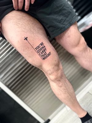 Elegant blackwork lettering tattoo on upper leg with a meaningful quote by Miss Vampira. A true work of art!
