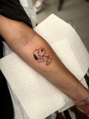 Get a unique Snoopy tattoo on your forearm in anime style and blackwork by the talented artist Miss Vampira.