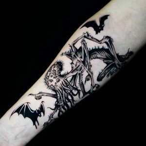 Get inked by Miss Vampira with this bold blackwork tattoo featuring a mesmerizing mix of a bat and Cthulhu designs on your forearm.