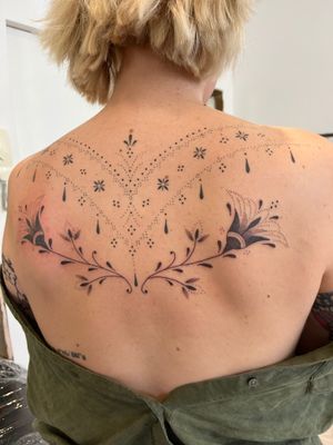 Indulge in intricate dotwork, fine line, and hand-poked details by Indigo Forever Tattoos on your back with this stunning floral design.