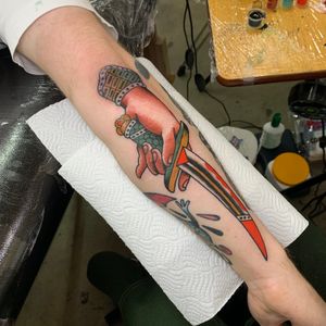 Get a bold traditional tattoo of a dagger and hand on your arm by the talented Andrea Furci.