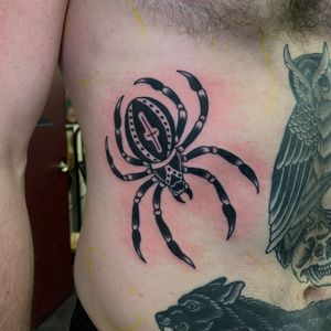 Get a striking traditional blackwork spider tattoo on your ribs by artist Andrea Furci. Bold and detailed design perfect for bold statement.