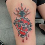 A stunning traditional tattoo of a flower and heart design on the upper leg by the talented artist Andrea Furci.