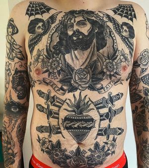 Classic black and gray traditional chest tattoo featuring a powerful sword and the image of Jesus, crafted by the talented artist Andrea Furci.