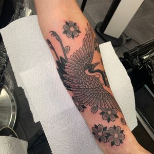 Exquisite Japanese-inspired tattoo on forearm featuring a graceful heron and delicate flower by renowned artist Andrea Furci.
