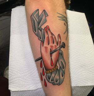 Get inked by Andrea Furci with a stunning traditional design of a hand holding a nail on your forearm. A timeless and bold choice for your next tattoo.