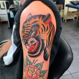 Get an eye-catching tiger tattoo on your upper arm done in the classic traditional style by talented artist Andrea Furci.