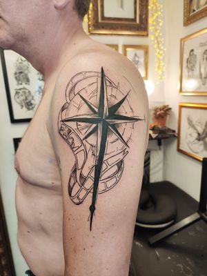 Get inked with a bold blackwork compass design on your upper arm, expertly crafted by tattoo artist Nikki Bostin.