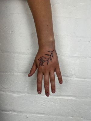 Experience the delicate beauty of dotwork and fine line floral design by Jack Henry Tattoo on your hand.