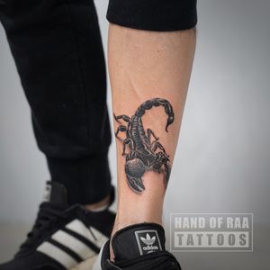Bold blackwork scorpion tattoo on the shin, created by the talented artist Raa. A powerful and striking design.