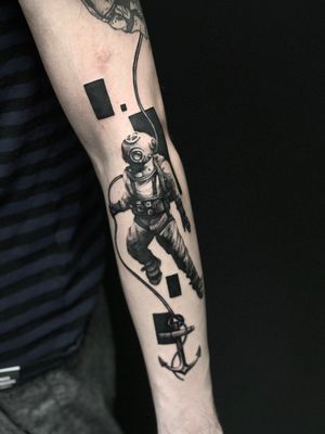 A stunning blackwork tattoo on the arm featuring an anchor and diving suit, expertly done by Artemis.