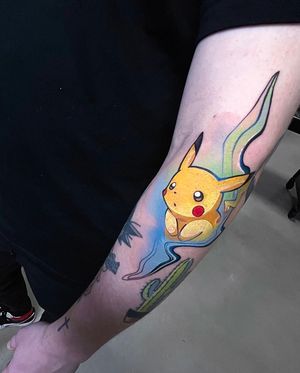 Get a striking anime-style Pikachu tattoo on your forearm by the talented artist Artemis. Stand out with this vibrant new school design!