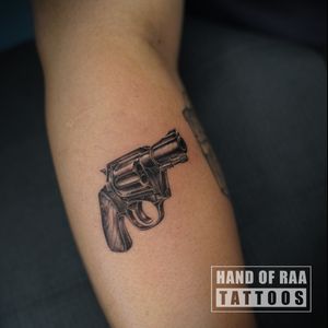 Check out this stunning black and gray gun revolver tattoo by Raa, beautifully inked on the lower leg.