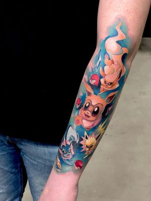Get a vibrant new school Eevee tattoo on your arm by the talented artist Artemis. Show off your love for anime and Pokemon with this unique piece!