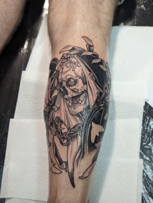 George Antony beautifully blends black and gray with traditional style in this stunning skull and skeleton with chain motif tattoo on the lower leg.