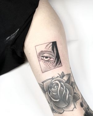 Get a bold and striking anime blackwork tattoo of a man on your upper arm, handcrafted by Artemis. Make a statement with this unique piece of art!