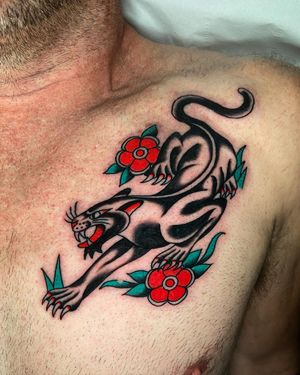 Ryan Goodrum expertly combines fierce panther and delicate flower motifs in this striking traditional style chest tattoo.