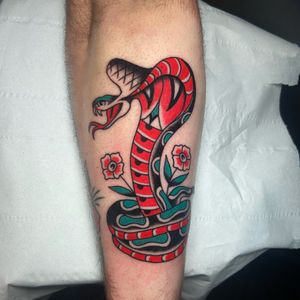 A stunning traditional style tattoo featuring a snake and flower motif, expertly done by Ryan Goodrum.