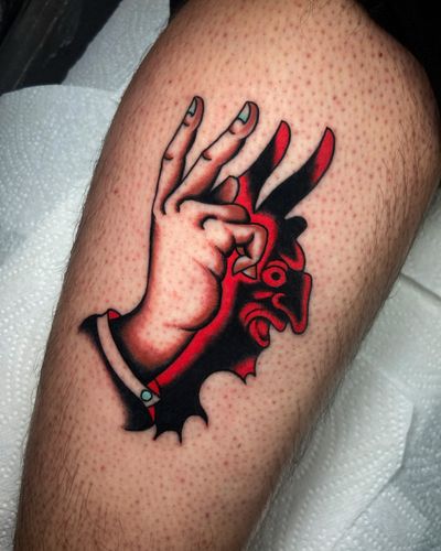 Get inked with a bold traditional devil hand design on your upper arm by artist Ryan Goodrum.