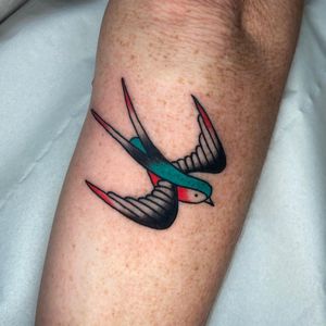 Get a classic traditional bird tattoo on your lower leg by the talented artist Ryan Goodrum. Timeless design that will stand the test of time.