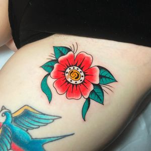 Get a gorgeous traditional flower tattoo on your upper leg by the talented artist Ryan Goodrum.