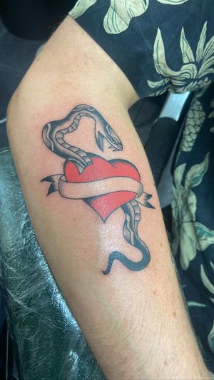 Get a classic yet bold design with this traditional snake and heart tattoo by Ryan Goodrum on your lower leg. Stand out with timeless ink!