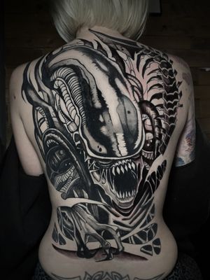 Kike Krebs created a stunning black and gray alien teeth tattoo on the back, blending mystery and beauty.